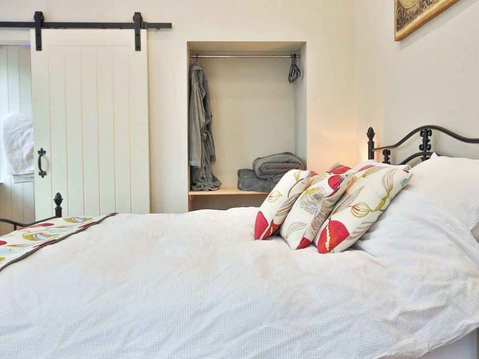 A bedroom with a bed and a shelf in the corner at The Groom's Cottage, at Ivy House near Louth