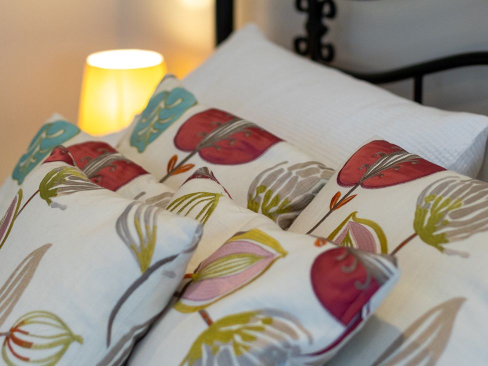 A bed with decorative pillows and a lamp at The Groom's Cottage, near Louth