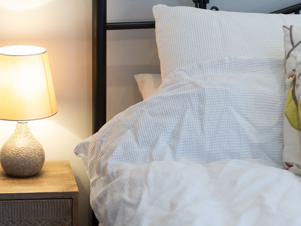 A bed with pillows and a lamp on a nightstand at The Groom's Cottage near Louth