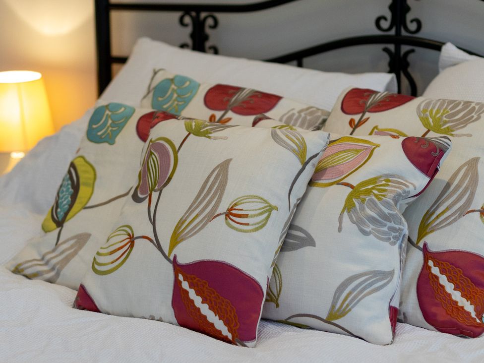 Pillows on a bed with a lamp in the background at The Groom's Cottage, near Louth