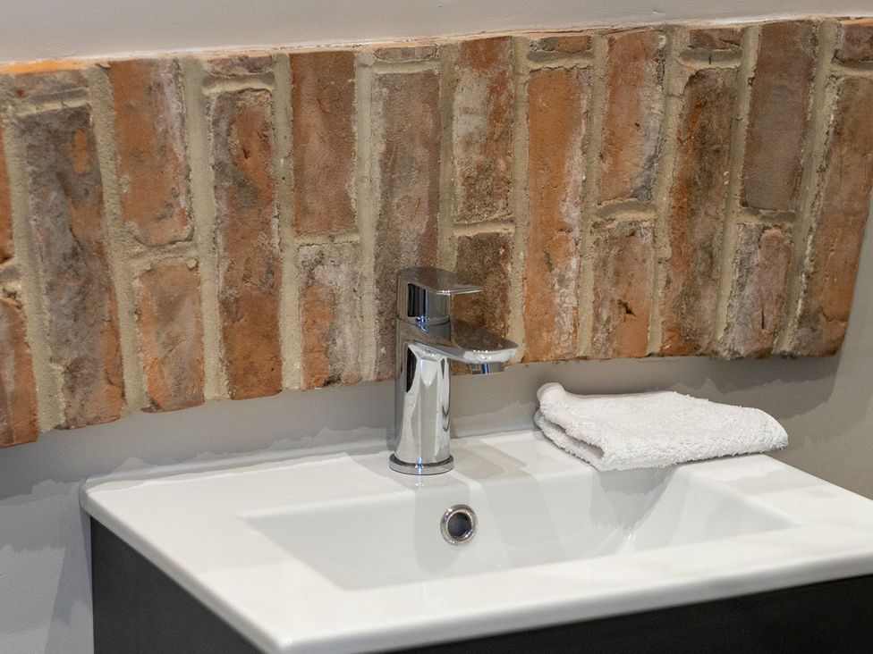 A sink with a faucet and towel in a bathroom at The Groom's Cottage, at Ivy House near Louth