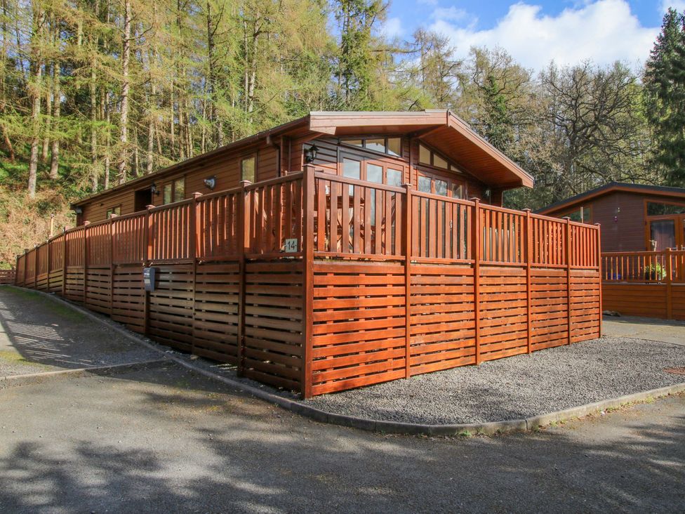 A wooden cabin with a fenced area and trees at No.14 Astbury Falls Luxury Retreat in Bridgnorth