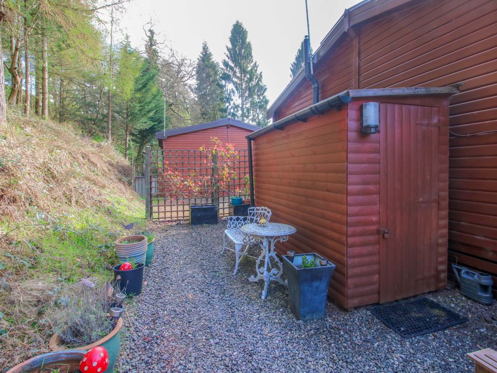 A garden with a table and chairs next to a shed at No.14 Astbury Falls Luxury Retreat in Bridgnorth