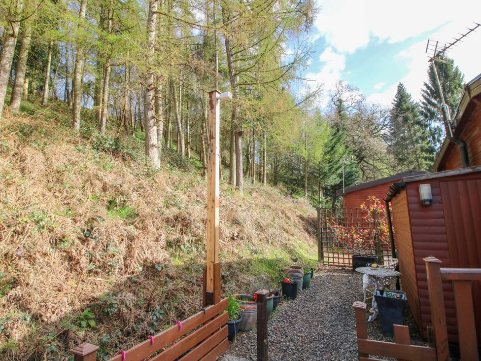 A garden with trees, gravel path, and plant pots at No.14 Astbury Falls Luxury Retreat in Bridgnorth