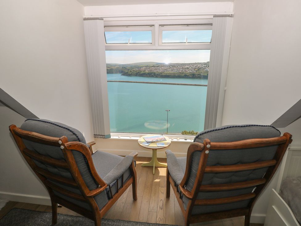 A sitting room with chairs and a table overlooking a view at Seaside Steps in Goodwick