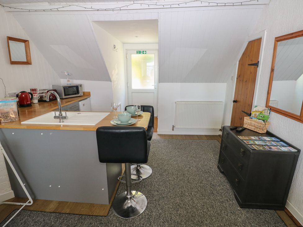 A kitchen with a sink and bar stools at Seaside Steps in Goodwick