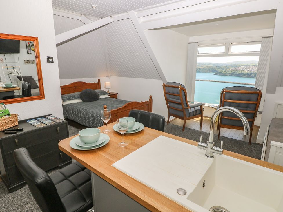 A studio room with a bed, dining area and view at Seaside Steps in Goodwick
