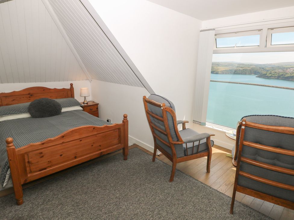 A bedroom with a bed and chairs at Seaside Steps Goodwick