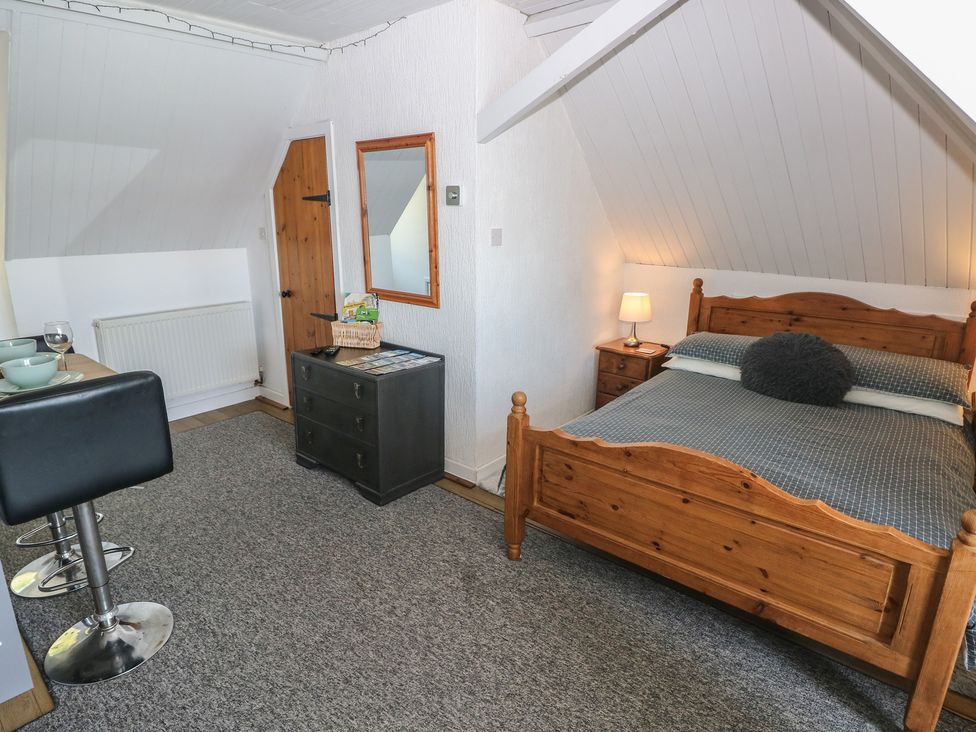 A bedroom with a wooden bed and a chest of drawers at Seaside Steps in Goodwick