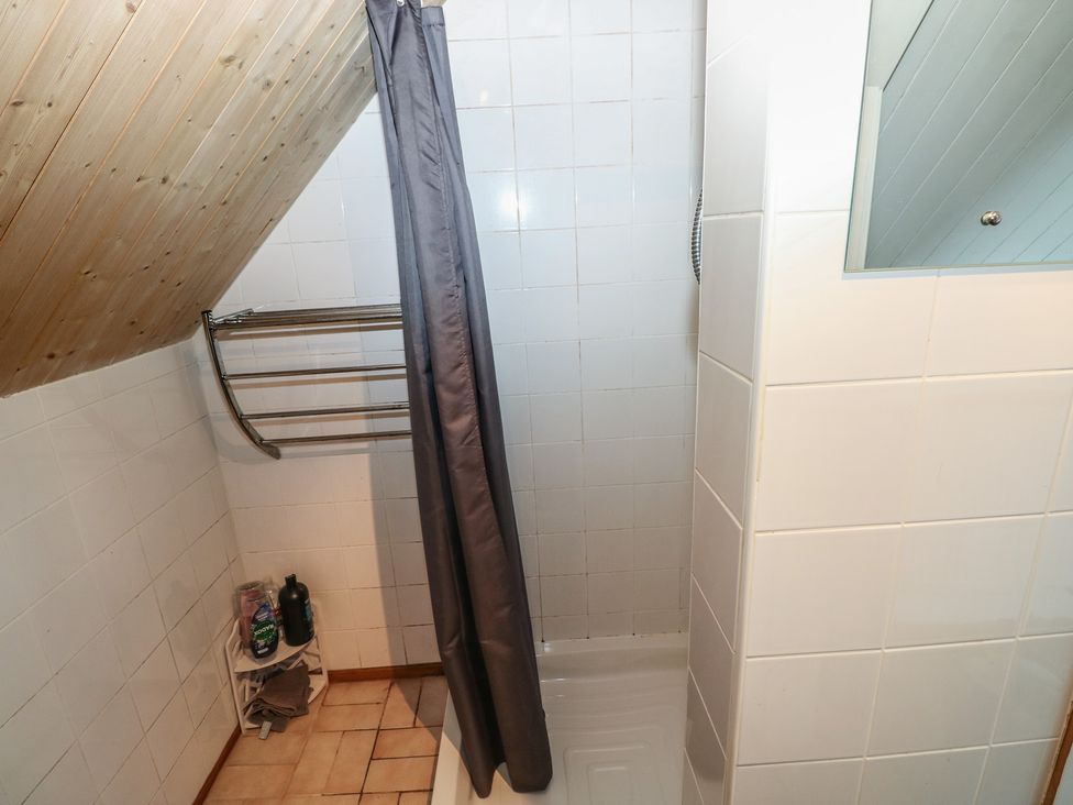 A bathroom with a shower curtain and towel rack at Seaside Steps in Goodwick