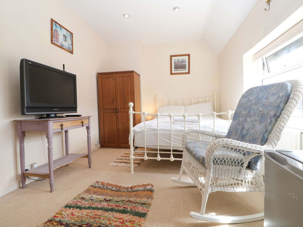 A bedroom with a bed, television, wardrobe, and rocking chair at Daisy Cottage 22 Chalkpit Terrace in Dorking