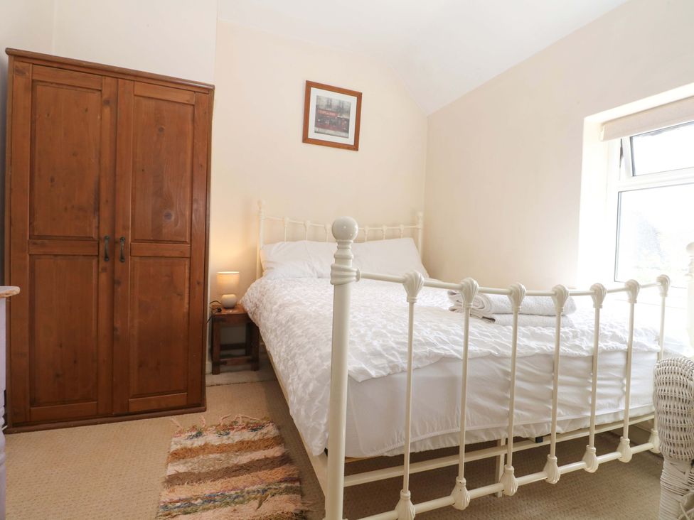 A bedroom with a bed and wardrobe at Daisy Cottage 22 Chalkpit Terrace Dorking
