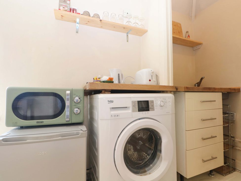A laundry room with a washing machine and microwave at Daisy Cottage 22 Chalkpit Terrace in Dorking