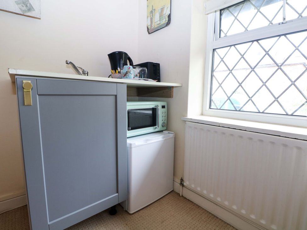 A kitchen area with a microwave and mini fridge at Daisy Cottage 22 Chalkpit Terrace Dorking