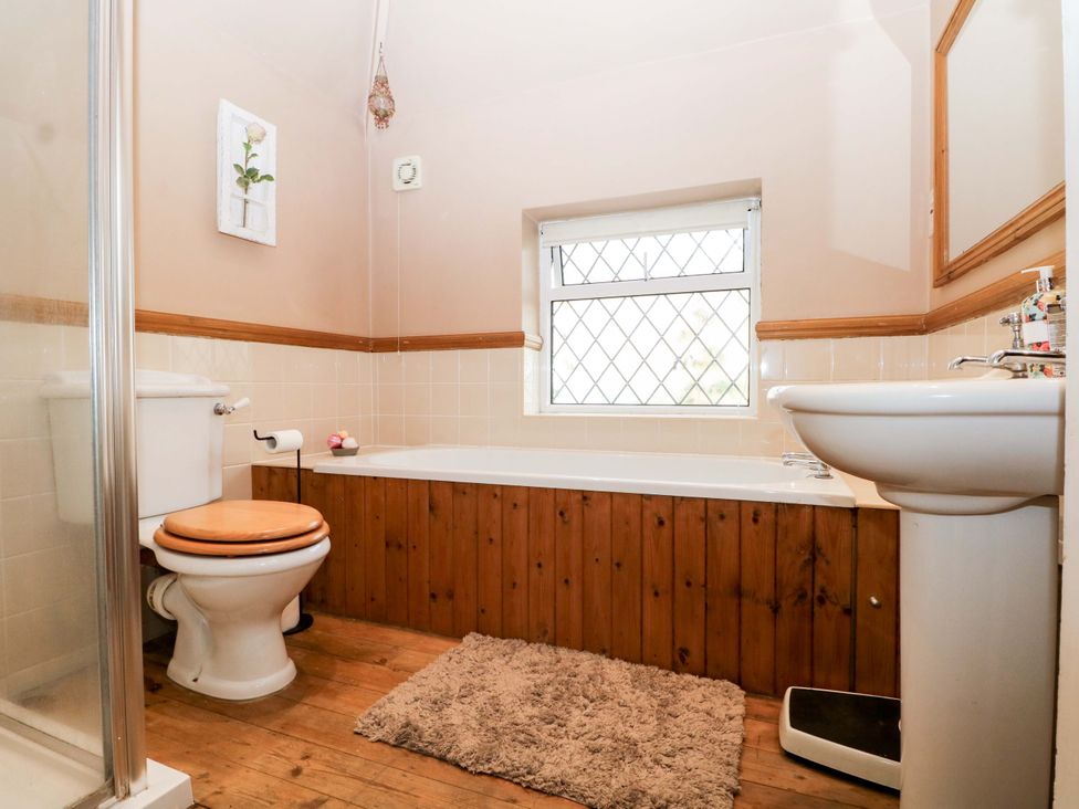 A bathroom with a bathtub, toilet, sink, and window at Daisy Cottage 22 Chalkpit Terrace Dorking