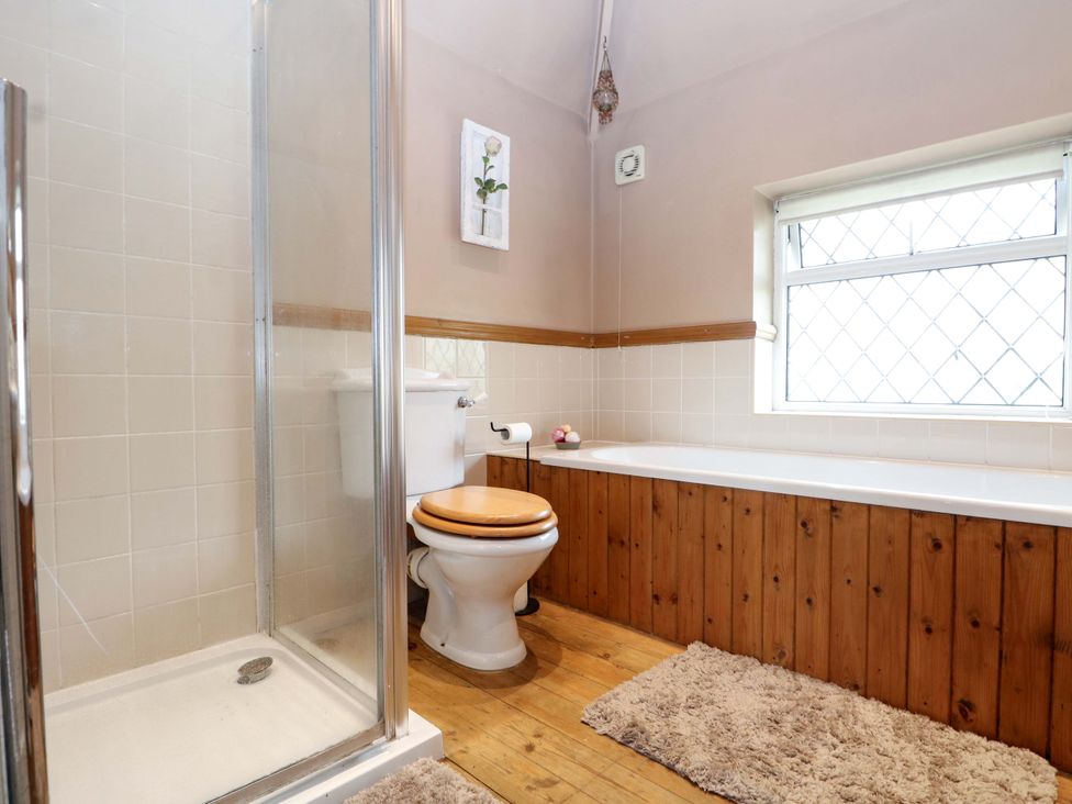 A bathroom with a shower, toilet, and bathtub at Daisy Cottage 22 Chalkpit Terrace Dorking