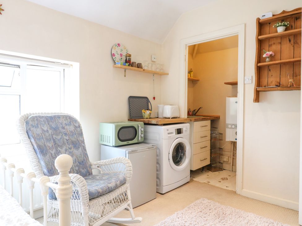 A kitchen with a washing machine and microwave at Daisy Cottage in Dorking