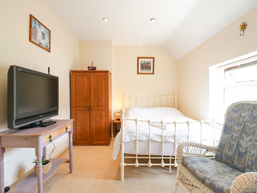 A bedroom with a bed and wardrobe at Daisy Cottage in Dorking