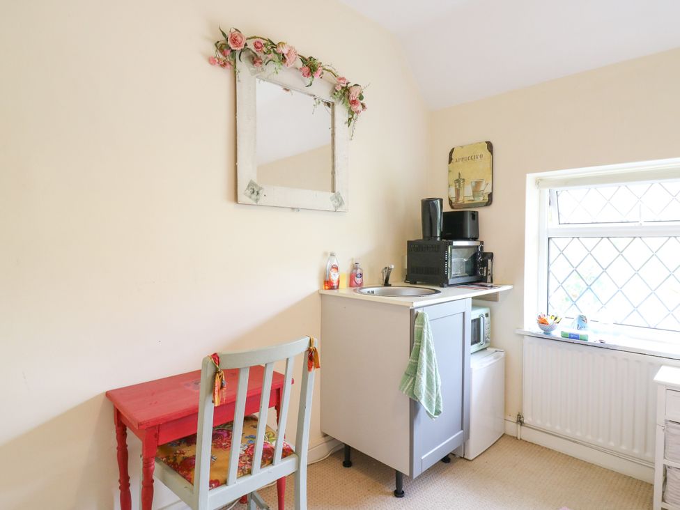 A kitchen with a table, chair, and appliances at Daisy Cottage in Dorking