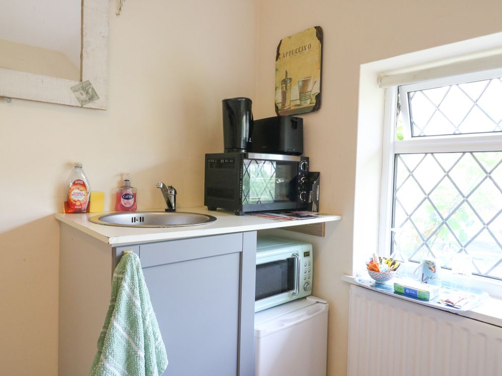 A kitchen area with a sink and coffee maker at Daisy Cottage in Dorking