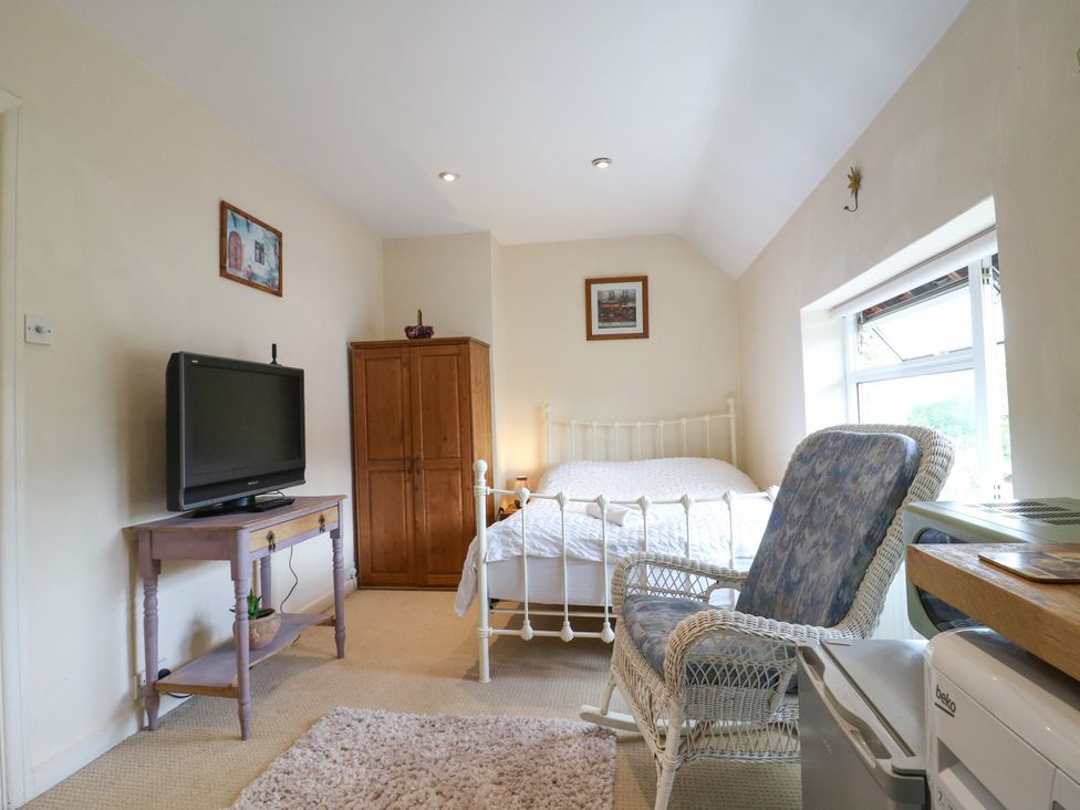 A bedroom with a bed and television at Daisy Cottage in Dorking