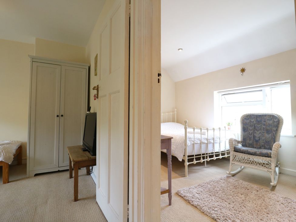 A bedroom with a bed and wardrobe at Daisy Cottage in Dorking