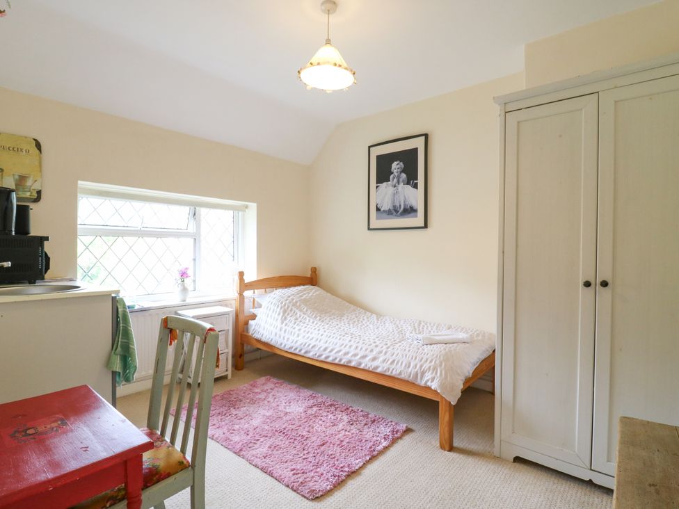 A bedroom with a single bed and wardrobe at Daisy Cottage in Dorking