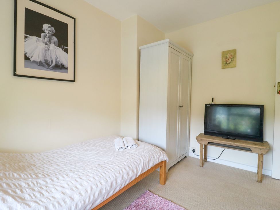 A bedroom with a bed and a television at Daisy Cottage in Dorking