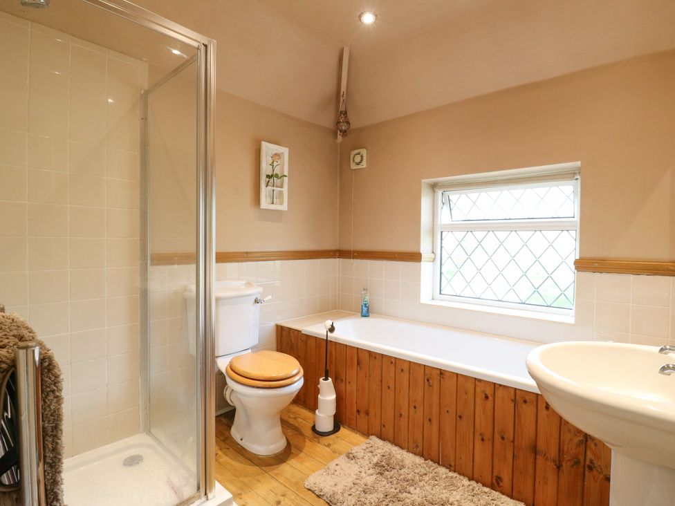 A bathroom with shower, bathtub, sink, and toilet at Daisy Cottage in Dorking