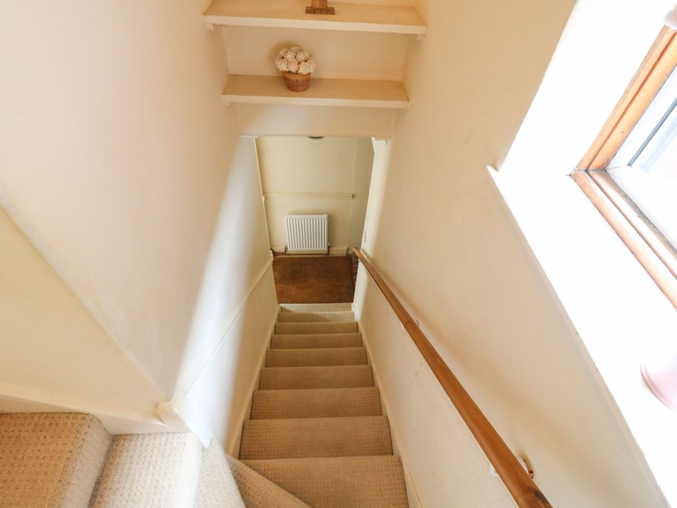 A staircase with handrail and shelf at Daisy Cottage in Dorking