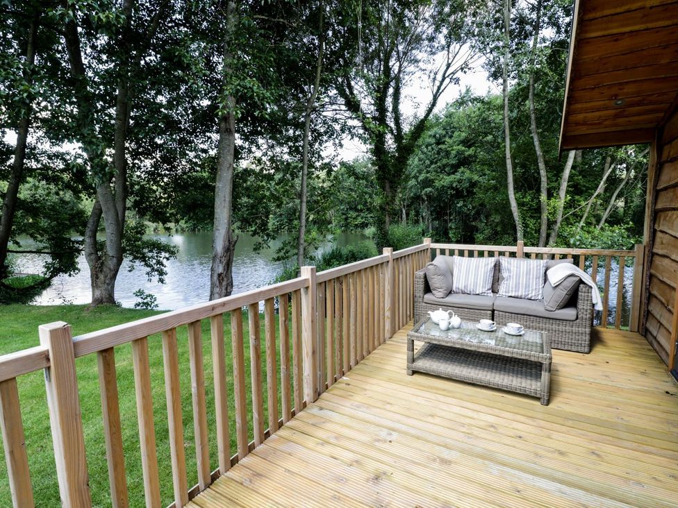 An outdoor seating area with a sofa and coffee table overlooking a lake at Skylark in Ross-on-Wye
