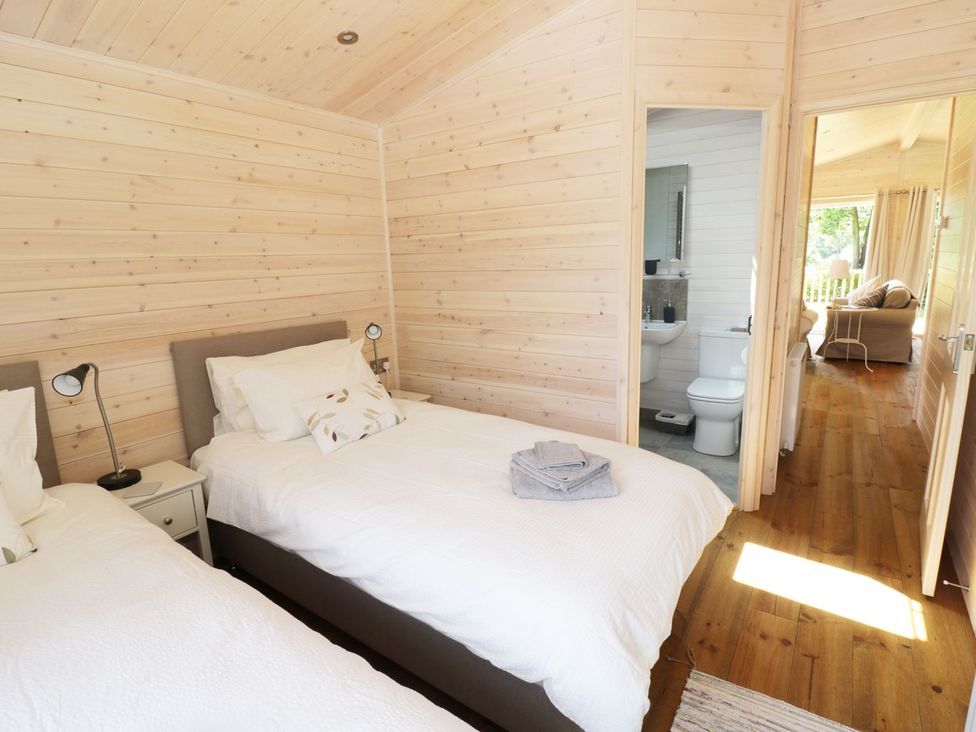 A bedroom with two beds and an adjacent bathroom at Skylark in Ross-on-Wye