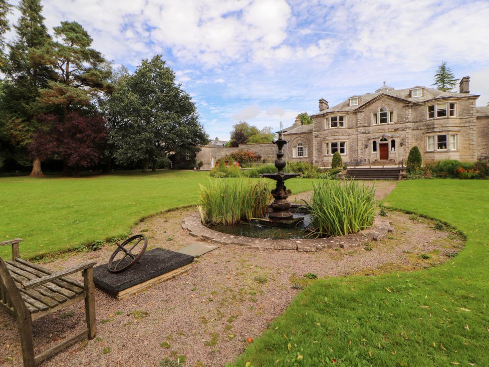 A garden with a fountain and a house in the background at Rochester Apartment in Orton
