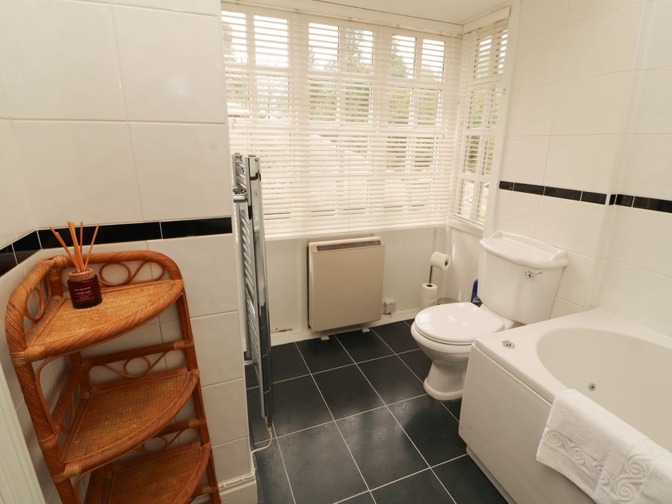 A bathroom with a tub, toilet, and shelves at Rochester Apartment in Orton