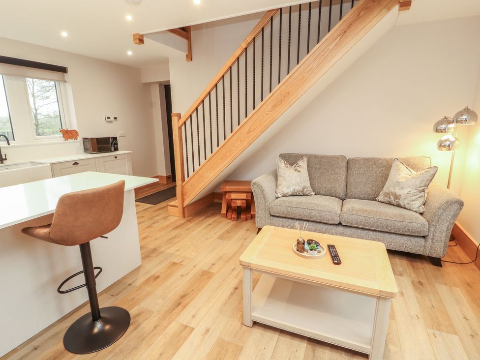A living room with a sofa, coffee table, and kitchen area at The Gate House Annexe in Cockermouth