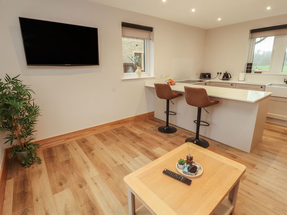 A kitchenette with bar stools and a television at The Gate House Annexe in Cockermouth
