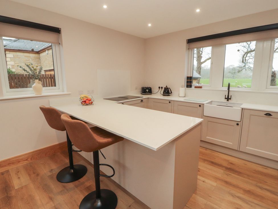 A kitchen with bar stools and a sink at The Gate House Annexe Cockermouth