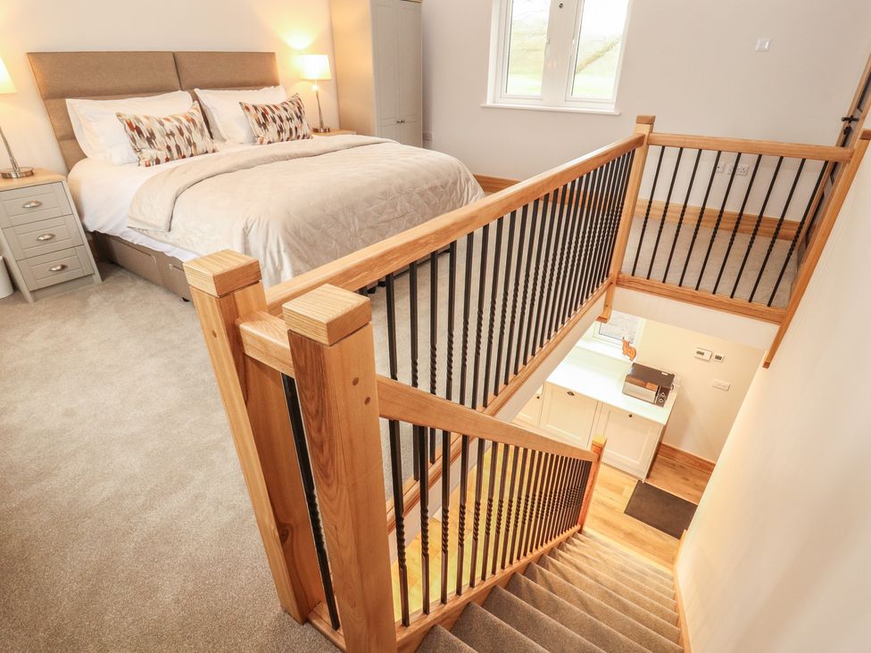 A bedroom with a bed and staircase leading to a lower floor at The Gate House Annexe in Cockermouth