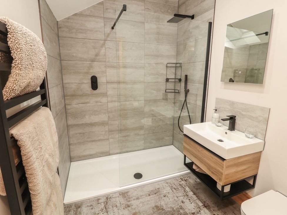 A bathroom with a shower, sink, and towels at The Gate House Annexe in Cockermouth