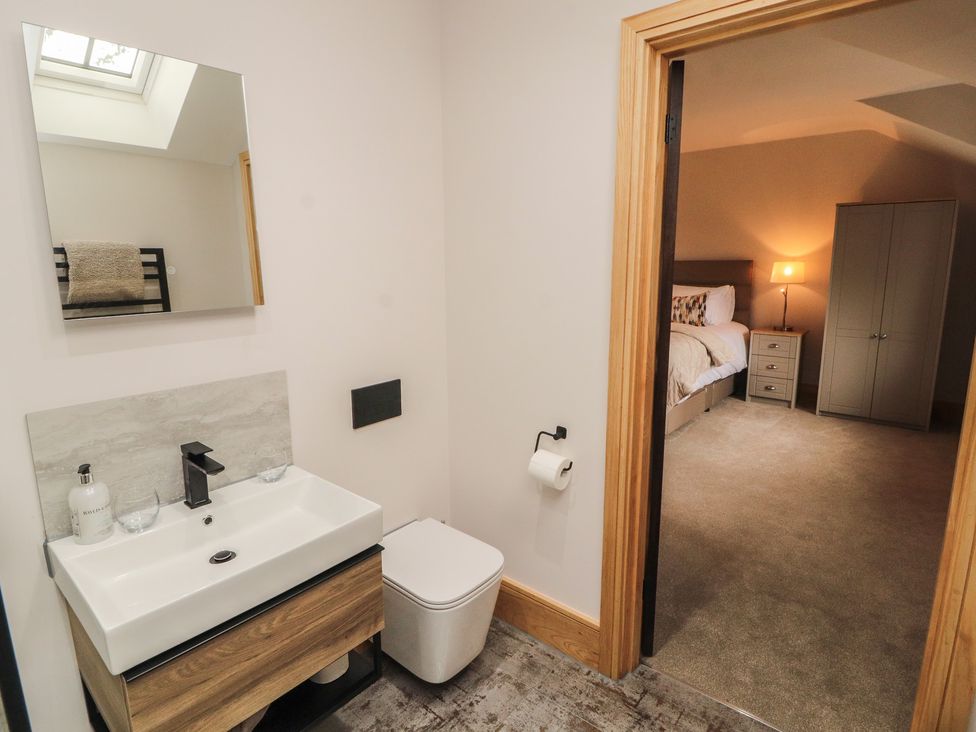 A bathroom with a sink and toilet leading to a bedroom at The Gate House Annexe Cockermouth