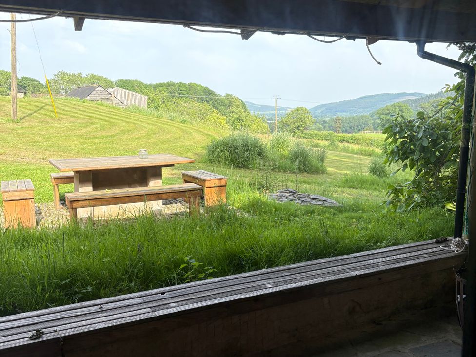 A table and benches in a grassy field at Walnut Tree Lodge WITH hot tub Presteigne