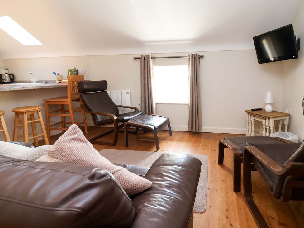 A living room with a sofa and kitchen area at Pen Y Grisiau in Mold