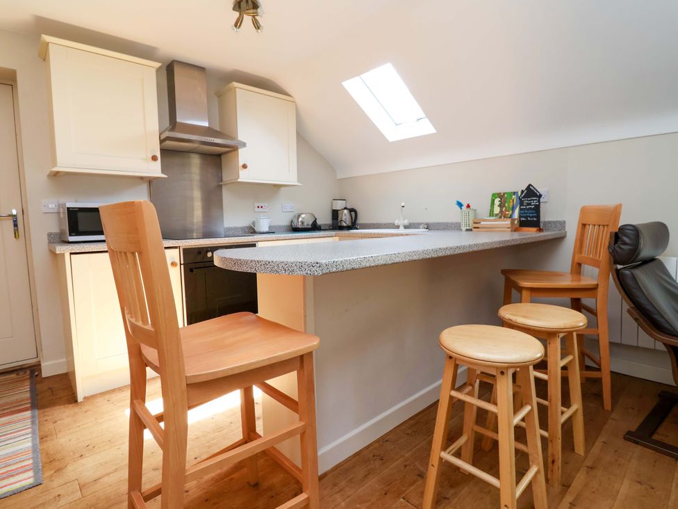 A kitchen with bar stools and appliances at Pen Y Grisiau in Mold
