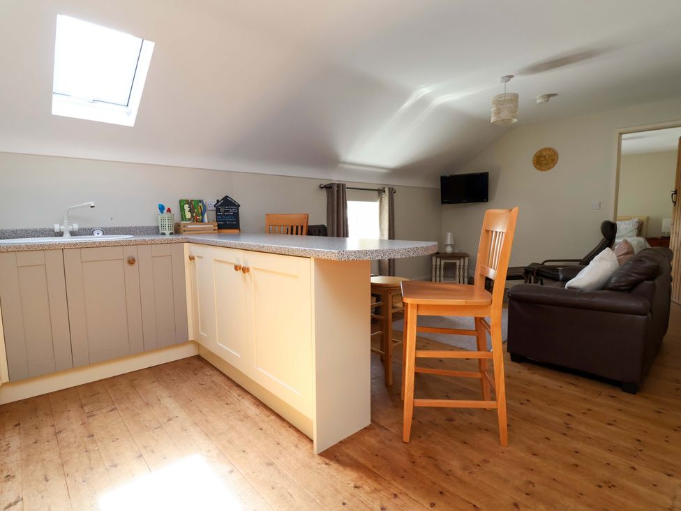 A kitchen with a counter and stools at Pen Y Grisiau in Mold