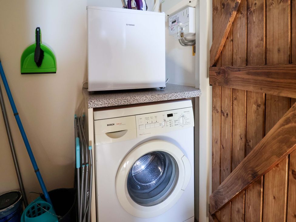 A laundry room with a washing machine and refrigerator at Pen Y Grisiau in Mold