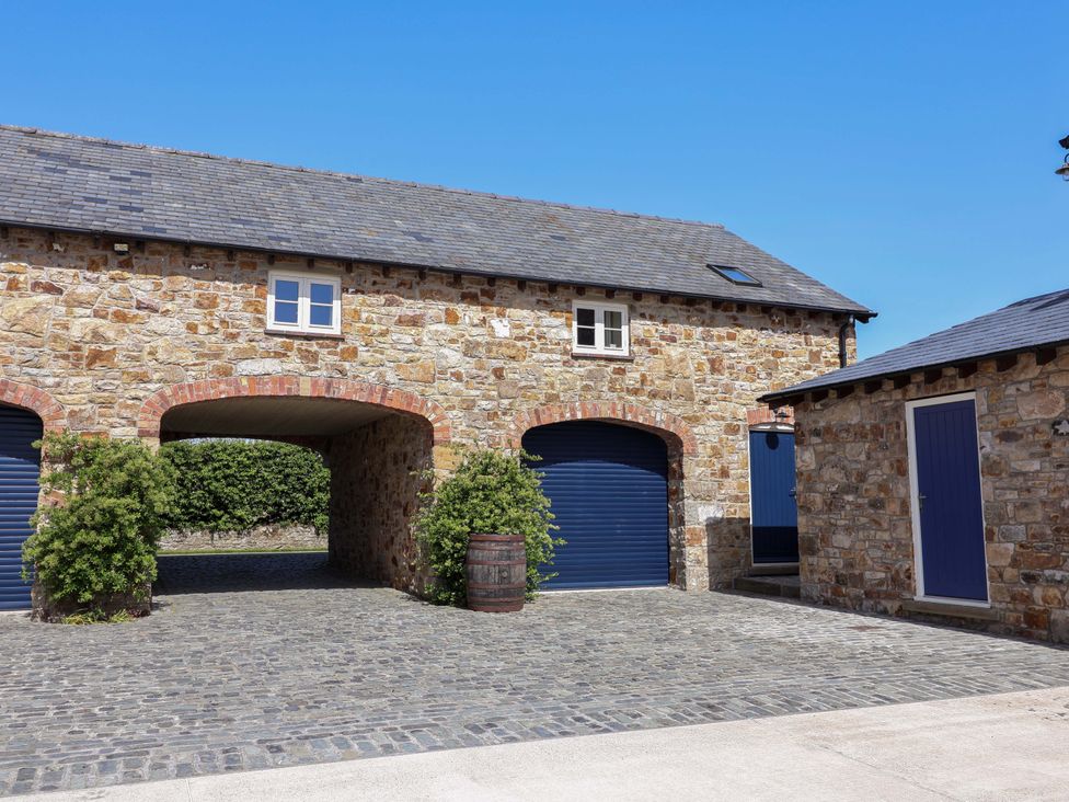 An outdoor view of a stone building with archway and garage doors at Pen Y Grisiau, Mold