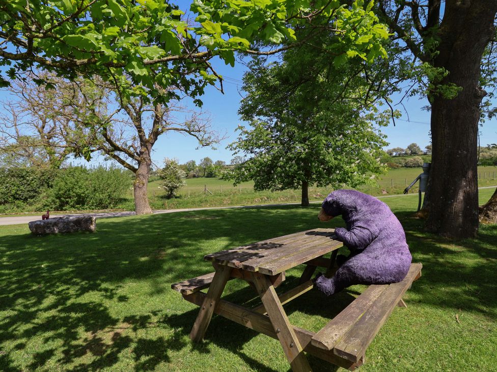An outdoor area with a picnic table and a bear statue at Pen Y Grisiau in Mold