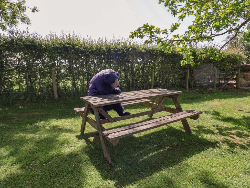 A bear sitting at a picnic table in a garden at Pen Y Grisiau in Mold