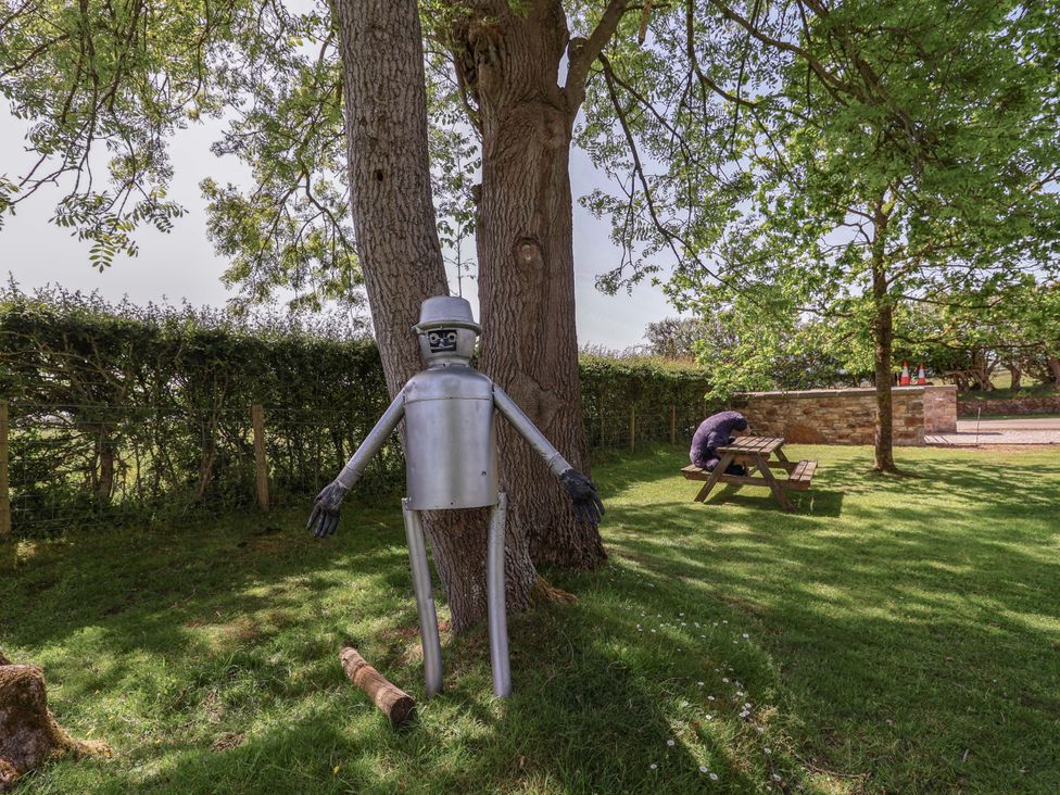 A metal figure near a tree and picnic table in a garden at Pen Y Grisiau in Mold