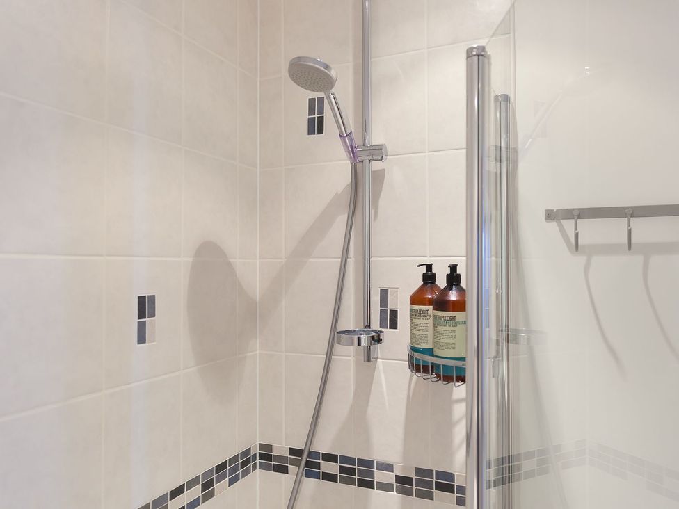 A shower with tiles and toiletries at Anchors Rest in St. Ives